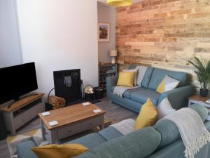 a living room with a blue couch and a tv at Y Bwthyn in Llanbedr