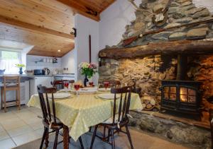 a dining room with a table and a stone fireplace at Y Bwthyn in Abererch