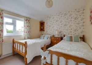 two twin beds in a bedroom with floral wallpaper at Y Bwthyn in Abererch