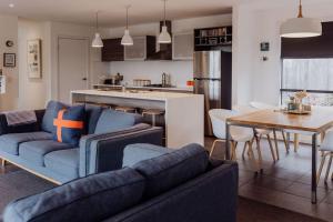 een woonkamer met een bank en een tafel en een keuken bij Lifebuoy Beach House Bicheno in Bicheno