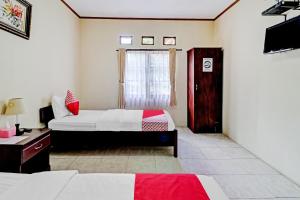 1 dormitorio con 2 camas y TV. en Collection O 90461 Graha Atmadja Syariah Guest House, en Bandung