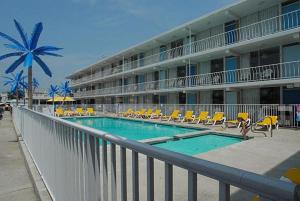 a hotel with a swimming pool with chairs and a building at Blue Palms Resort in Wildwood
