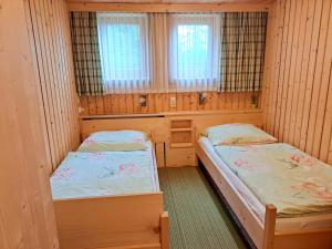 two beds in a room with wooden walls and windows at Chalet Faschingalm in Debant