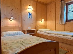 two beds in a room with wooden walls at Chalet Faschingalm in Debant