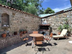 Zografia cottage في Lámpou Mýloi: فناء مع طاولة وكراسي ومدفأة