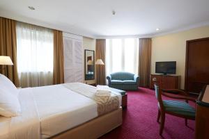una camera d'albergo con letto, sedia e TV di Grand Pacific Hotel a Kuala Lumpur