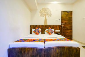 a bedroom with a large bed with a tree on the wall at FabExpress Shalimar in Mumbai