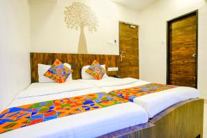 a bedroom with two beds and a tree mural on the wall at FabExpress Shalimar in Mumbai
