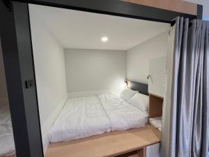 Dormitorio pequeño con cama y espejo en W2 Hostel en Chiang Mai
