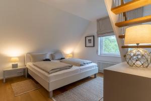 a bedroom with a bed with two lamps and a window at Reetdachhaus Dünen Lounge in Böhl