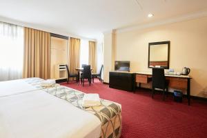 a hotel room with a bed and a desk and a mirror at Grand Pacific Hotel in Kuala Lumpur