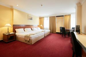 una camera d'albergo con un grande letto e una scrivania di Grand Pacific Hotel a Kuala Lumpur