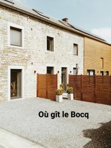 un edificio de ladrillo con una valla y las palabras nuestro regalo la booco en Où gît le Bocq Spa privatif, en Ciney