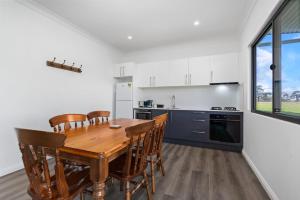 a kitchen with a wooden table and chairs at Glenowrie Cottage - 1 King 2 Singles - Near Cadia in Millthorpe