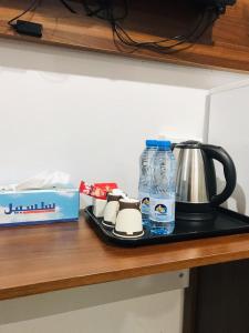 MY HOTEL Nizwa Residence Hotel Apartement نزوى ريزيدنس في نزوى‎: كونتر مع وعاء القهوة وزجاجة من الماء