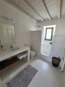 Aviola Mykonos في فتيليا: حمام أبيض مع حوض ومرحاض