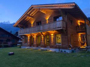 una casa de madera con una terraza en el césped en Chalet Vicky et Nino, en Les Diablerets