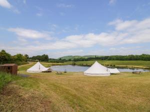 a group of tents in a field next to a lake at Tumbling Tom in Worcester