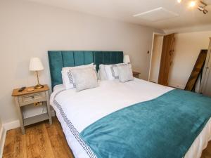 een slaapkamer met een groot bed met een blauw hoofdeinde bij The Coach House At The Gables in Shrewsbury