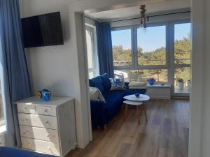 un salon avec un canapé bleu et une grande fenêtre dans l'établissement Apartamenty Pisakowe - Apartament Śledzik, à Rowy