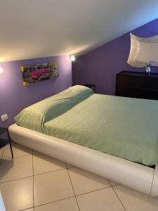 a bed in a bedroom with a purple wall at CASA VACANZA DAMAR in Mascali