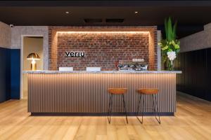 a bar with two stools in front of a brick wall at Veriu Collingwood in Melbourne