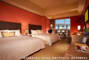 2 bedden in een hotelkamer met oranje muren bij Leofoo Resort Guanshi in Guanxi