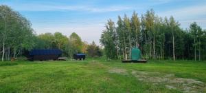 un campo con dos mesas de picnic y un contenedor verde en Ku:Kärg, en Põldeotsa
