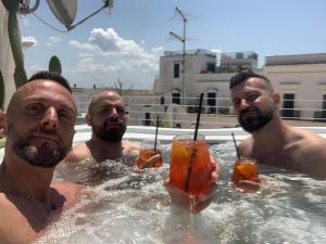 three men in a swimming pool holding drinks at B&B Salentus in Gallipoli