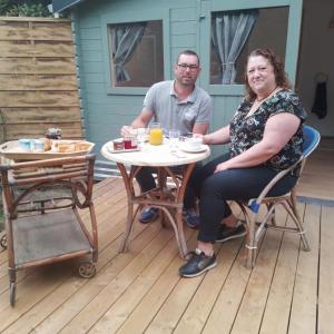 a man and a woman sitting at a table on a deck at La cabane de Mimi la Sardine in Saint-Gervais en-Belin