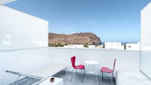 Habitación blanca con mesa y 2 sillas rosas en Hotel Spa Calagrande Cabo de Gata, en Las Negras