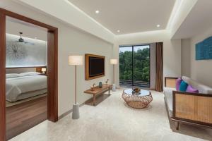 1 dormitorio con 1 cama, TV y sofá en Sheraton Grand Chennai Resort & Spa en Mahabalipuram