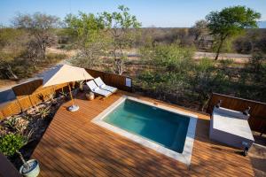 an outdoor deck with a swimming pool and an umbrella at Ntoma House in Hoedspruit