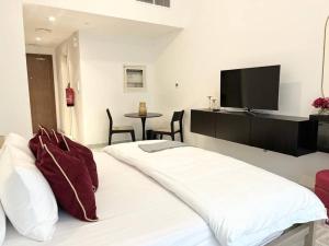 a bedroom with a white bed with a flat screen tv at Cozy Studio In Masdar City in Al Qurayyah