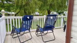 - deux chaises bleues assises sur une terrasse couverte dans l'établissement 3 Bed Caravan at Parkdean Resort Southview Skegness on a Fishing Lake, à Lincolnshire