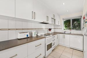 a white kitchen with white appliances and a window at Walpole Beachside Oasis in Cowes