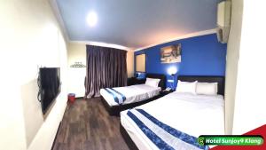two beds in a hotel room with blue walls at Hotel Sunjoy9 Klang in Klang