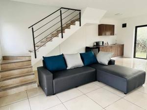 ein Wohnzimmer mit einem schwarzen Sofa und einer Treppe in der Unterkunft Green Village Duplex in Grand-Gaube