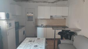 a kitchen with white cabinets and a table and a couch at Studio charmant in Fontenay-sous-Bois