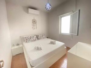 een witte slaapkamer met een bed en een raam bij Seamoon Home Nettuno in Nettuno
