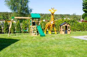 una estatua de jirafa parada junto a un parque infantil en PRZYSTANEK G&S, en Mikoszewo