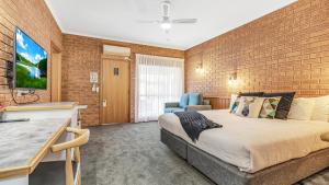 a bedroom with a large bed and a brick wall at Golden River Motor Inn in Moama