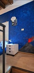 a bedroom with a blue wall with a bed and a dresser at Apartment mYourHome in Catania