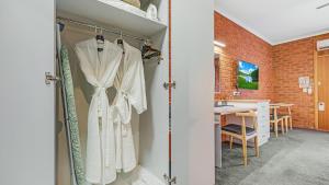 a bathroom with a closet with white dresses and a table at Golden River Motor Inn in Moama