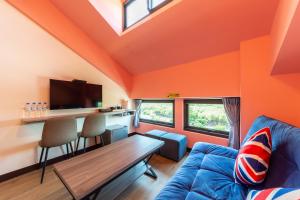 sala de estar de color naranja con sofá azul y mesa en Qun Xiang Hotel en Anping