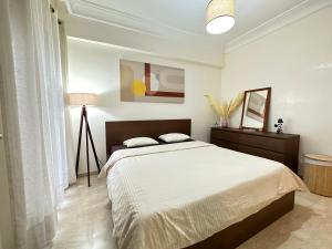 a white bedroom with a bed and a lamp at Cosy and greeny flat near oasis train and tramway in Casablanca