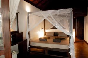 a bedroom with a bed with a canopy at Mambo’s hotel Arugam Bay in Pottuvil
