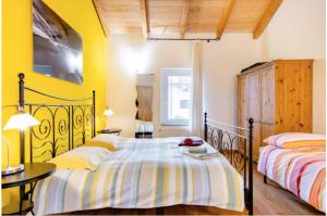 2 łóżka w sypialni z żółtymi ścianami i drewnianymi sufitami w obiekcie B&B Ai Tigli w mieście Udine
