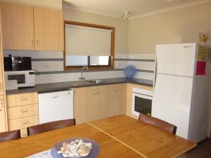 a kitchen with a table and a white refrigerator at Beachcomber Bliss in Smiths Beach +8 photos