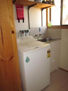 a small kitchen with a sink and a small refrigerator at Beachcomber Bliss in Smiths Beach